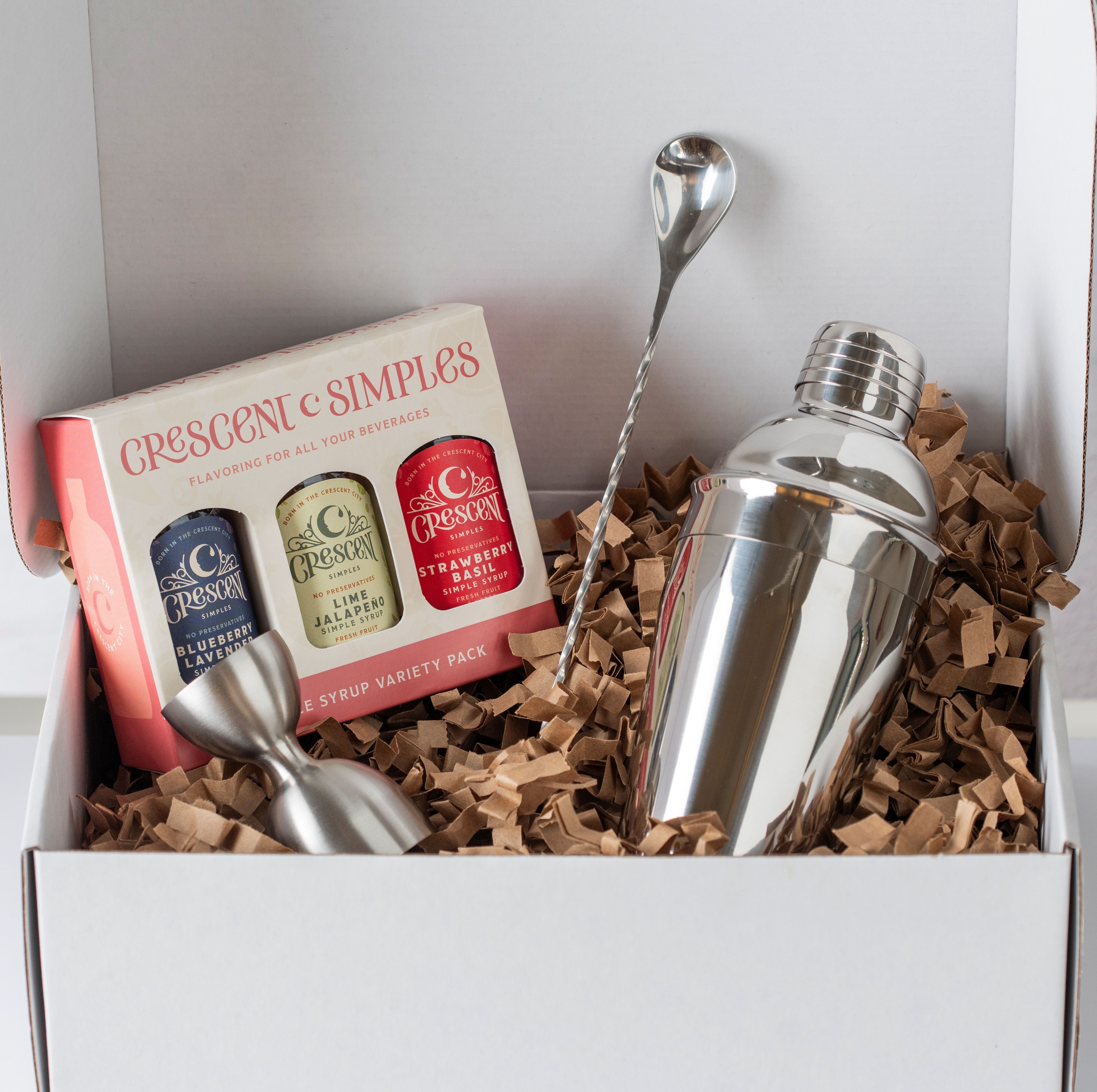 A gift box containing a simple syrup 3-pack, jigger, bar spoon, and cocktail shaker.