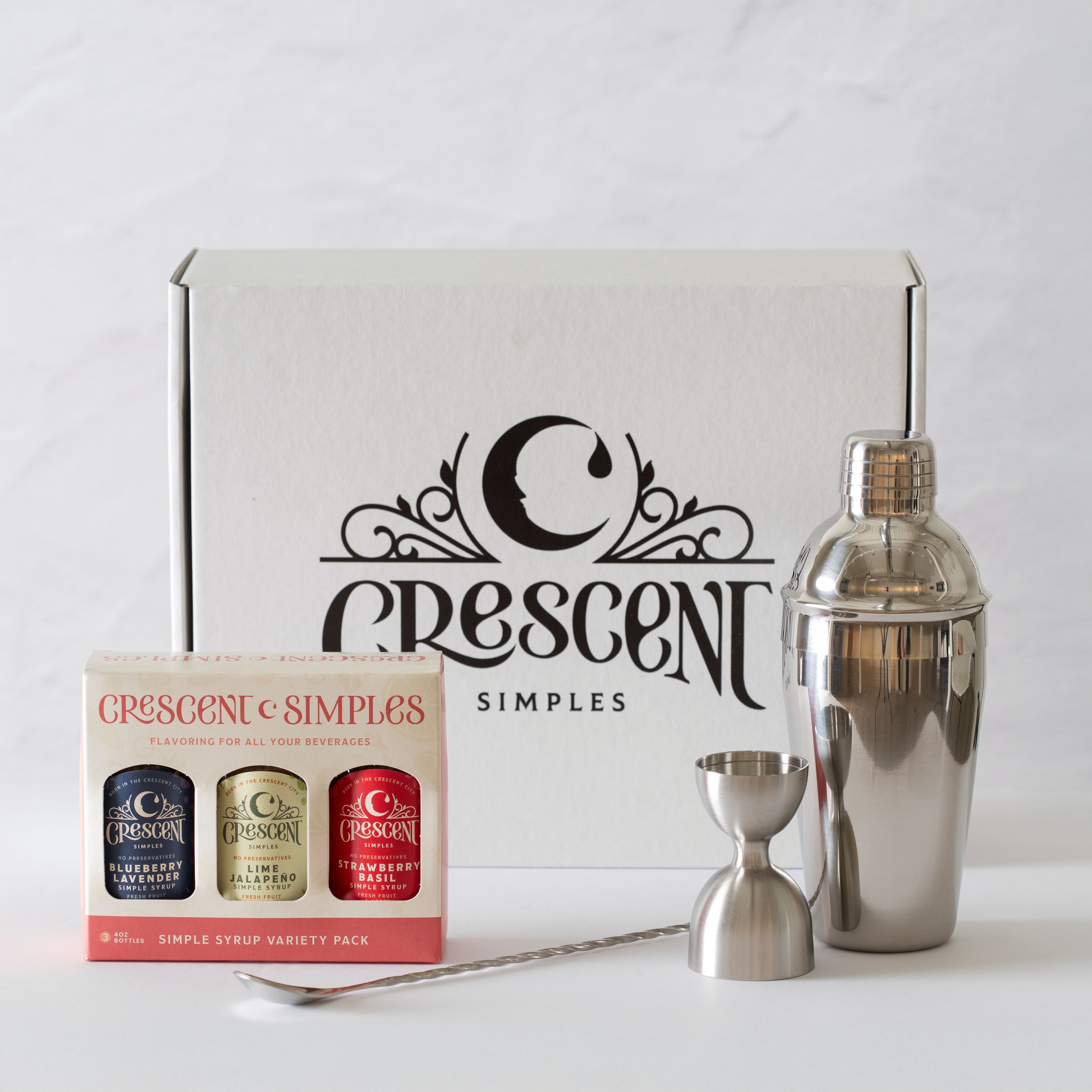A gift box containing a simple syrup 3-pack, bar spoon, jigger, and cocktail shaker.